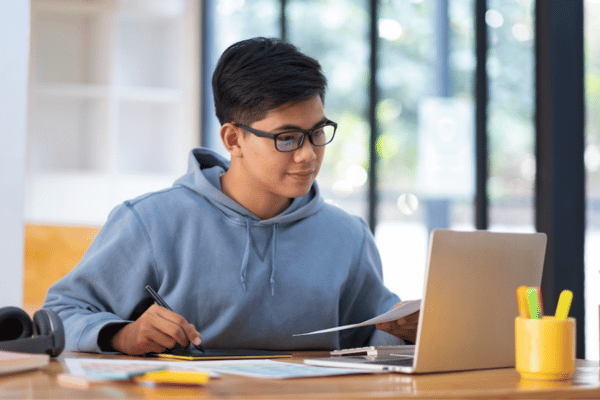 Young college student using computer and mobile device studying online